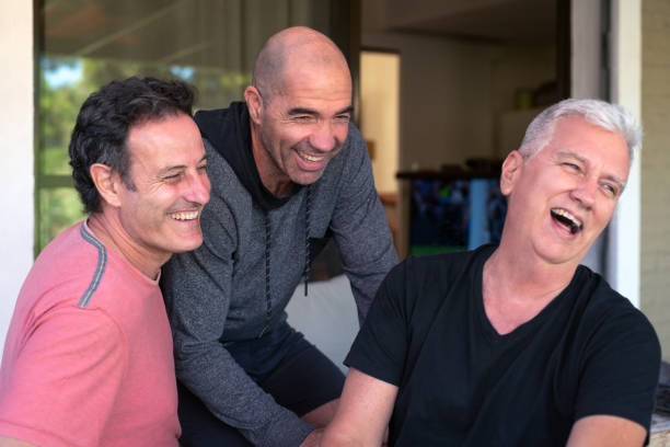 Three older male friends smiling and hugging, enjoying a day together.