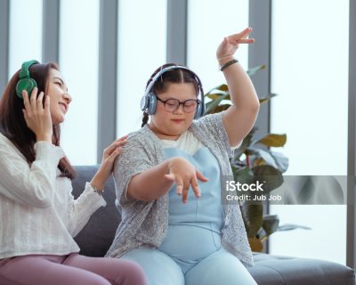 Down syndrome girl is listening to music and singing with her mother during her holiday home.