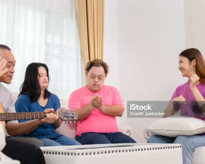 Senior man and grandchild having fun together while singing and playing the guitar in living room at home