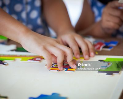 Child little girl hand trying to connect jigsaw puzzle piece to learn to find solution